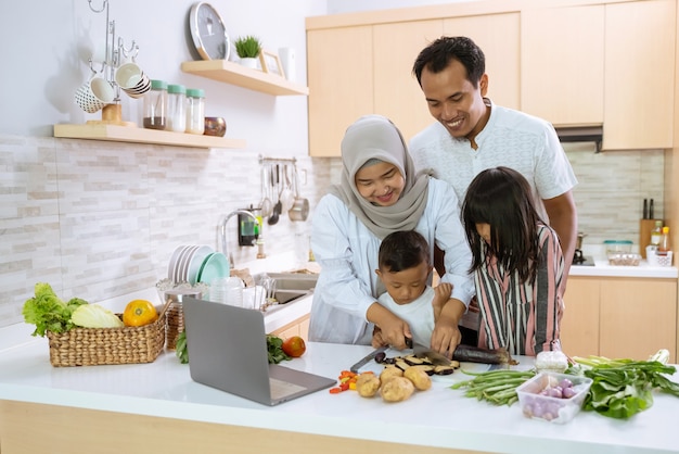 Los padres musulmanes y los niños disfrutan cocinando juntos la cena iftar durante el ayuno de Ramadán en casa