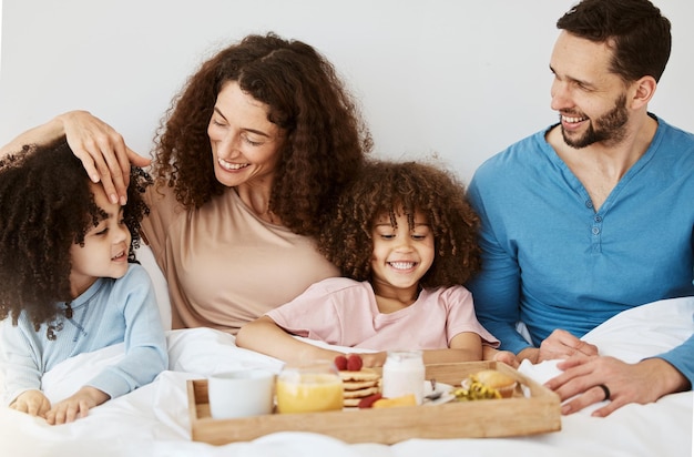 Los padres los niños y el desayuno en la cama por la mañana o emocionado por el amor la unión o el cuidado en las vacaciones madre padre y los niños en el dormitorio comida y sonreír juntos para la nutrición comer o hogar familiar feliz