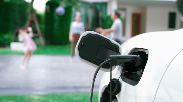 Los padres progresistas han regresado de recoger a su hija en la escuela con el concepto de vehículo eléctrico y estación de carga de energía renovable para automóviles eléctricos en casa Transporte ecológico alternativo