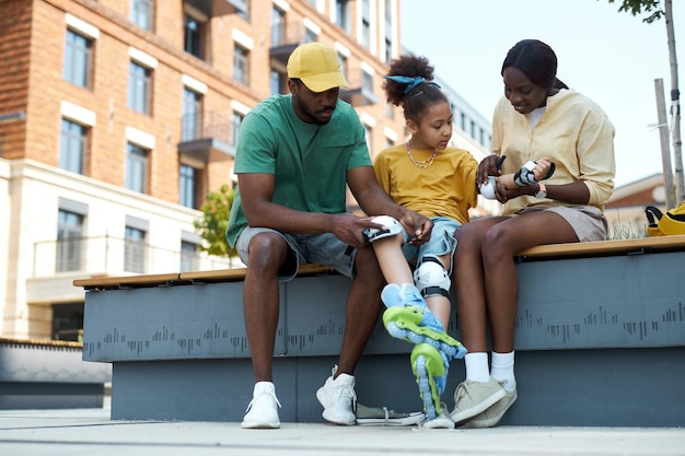 Padres que protegen a sus hijos antes de patinar durante su caminata al aire libre