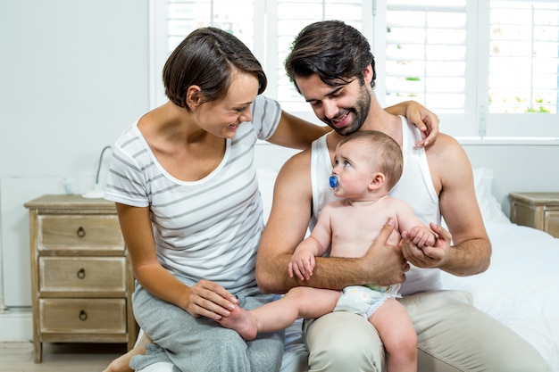 Foto padres sentados con hijo en la cama en casa