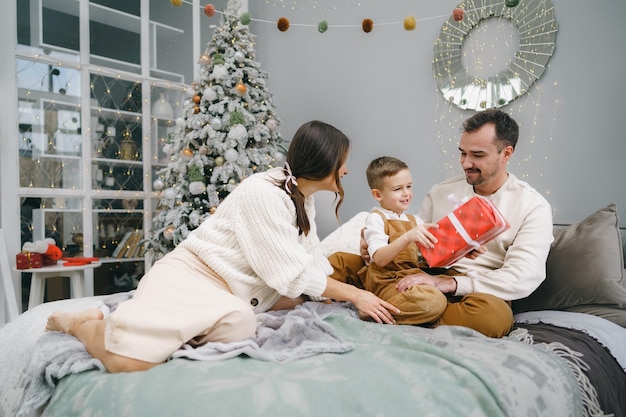 Padres sonrientes dando regalo de Navidad a su hijo en casa