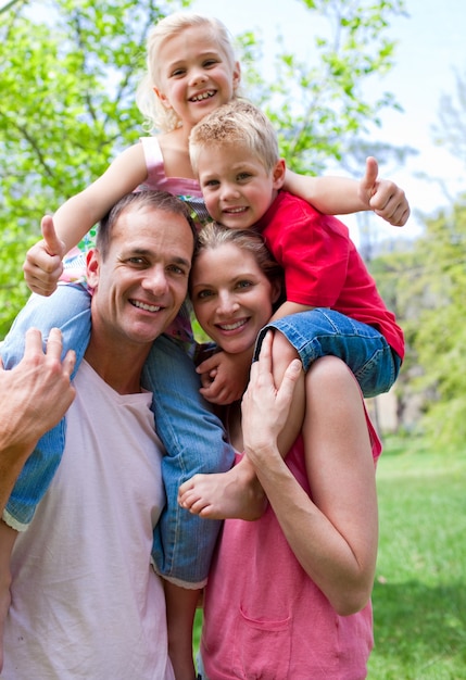 Foto padres sonrientes dando a sus hijos a cuestas paseo