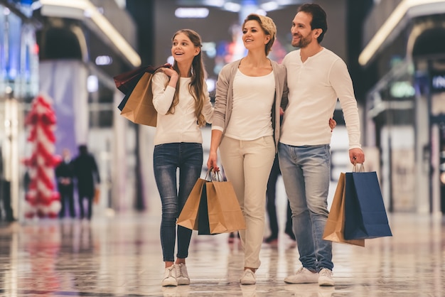 Foto los padres y su hija sostienen bolsas de compras.