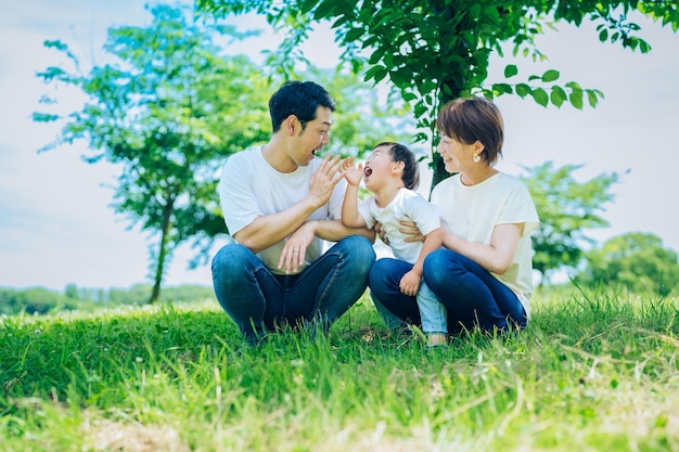 Los padres y su hijo sentados en un espacio verde soleado