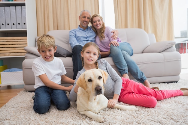 Los padres y sus hijos en el sofá con labrador