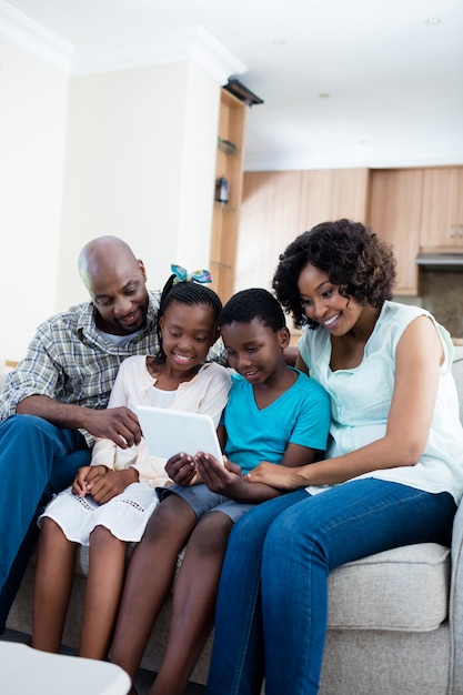 Los padres y sus hijos con tableta digital en la sala de estar