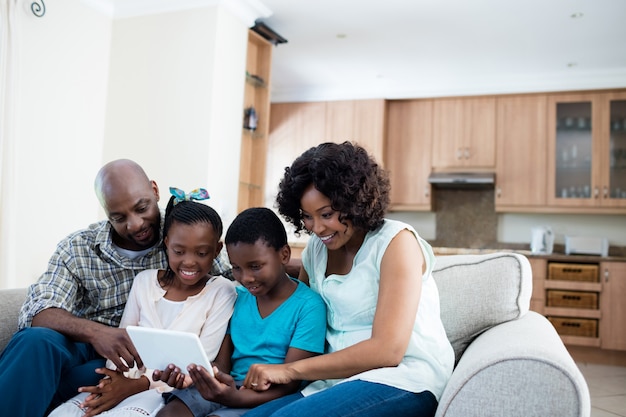 Los padres y sus hijos con tableta digital en la sala de estar