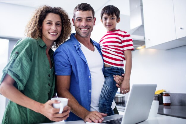 Padres usando laptop con hijo en la cocina