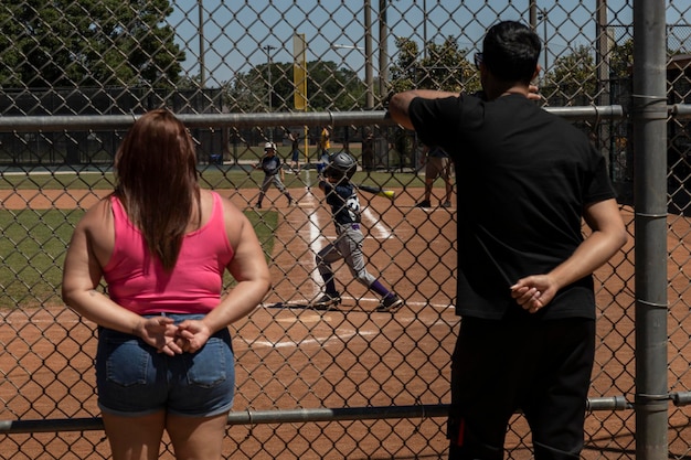 Padres viendo a sus hijos jugar al béisbol