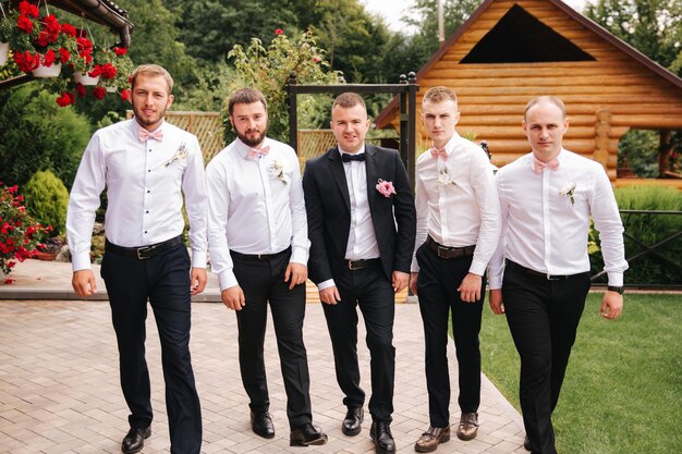 Padrinho elegante com noivo em pé no quintal e se preparar para a cerimônia de casamento amigo