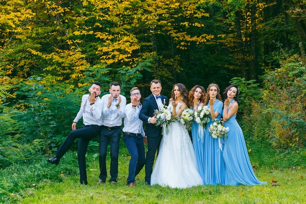 Padrinhos e damas de honra mandam um beijo no ar para a câmera na natureza no verão