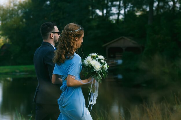 Foto padrinos de boda y damas de honor caminando cerca del estanque.