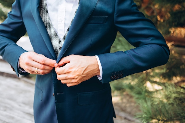 Padrinos de boda con estilo que ayudan al novio feliz que se prepara en la mañana para la ceremonia de boda. Hombre de lujo en traje en la habitación. día de la boda.