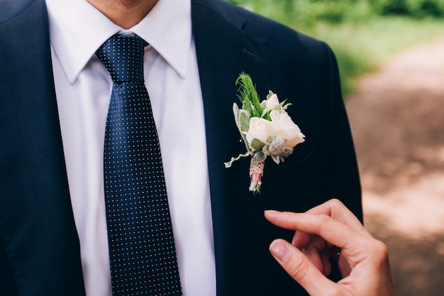 Padrinos de boda con estilo que ayudan al novio feliz que se prepara en la mañana para la ceremonia de boda. Hombre de lujo en traje en la habitación. día de la boda.