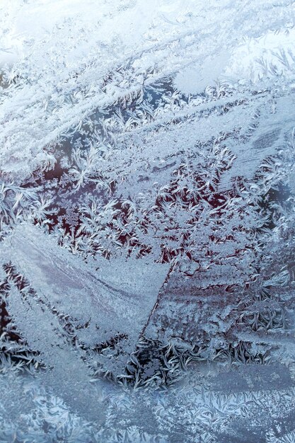 Padrões gelados no vidro contra o fundo do sol da manhã