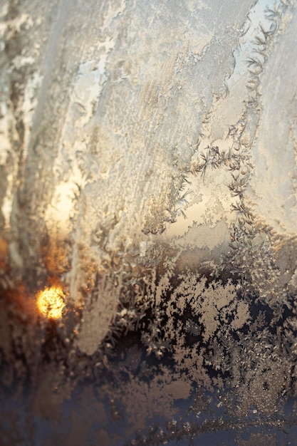 Padrões gelados no vidro contra o fundo do sol da manhã