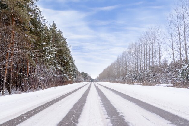 Padrões na rodovia de inverno na forma de quatro linhas retas. Estrada nevada no fundo da floresta coberta de neve. Paisagem de inverno.