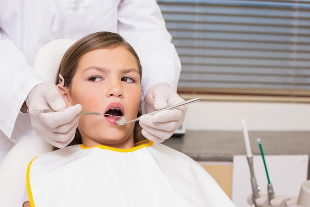Pädiatrischer Zahnarzt, der Patientenzähne im Zahnarztstuhl überprüft