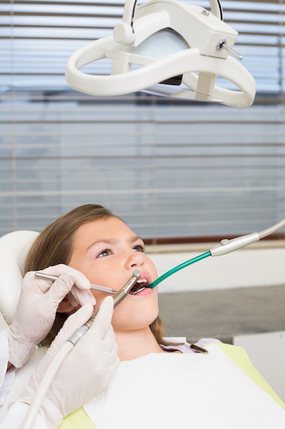 Pädiatrischer Zahnarzt, der Zähne der kleinen Mädchen im Zahnarztstuhl überprüft