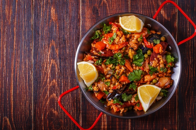 Paella com frango, chouriço, frutos do mar, verduras e açafrão servidos em panela tradicional