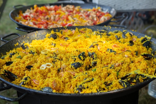 Paella comida tradicional espanhola. paella preparada em uma panela grande na rua em chamas