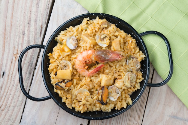 Paella de legumes com frutos do mar em um de madeira