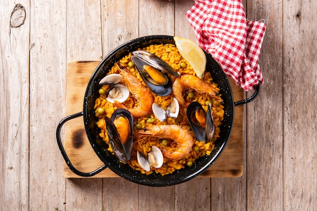 Paella espanhola tradicional de frutos do mar em mesa de madeira