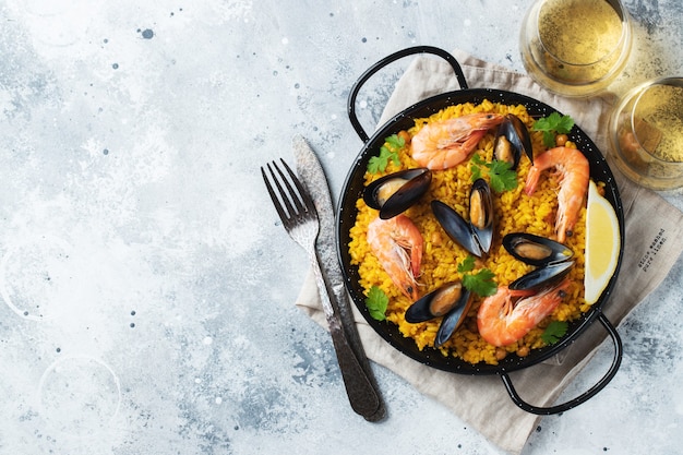 Paella espanhola tradicional de frutos do mar na panela com grão de bico, camarão, mexilhão, lula. Vista do topo.