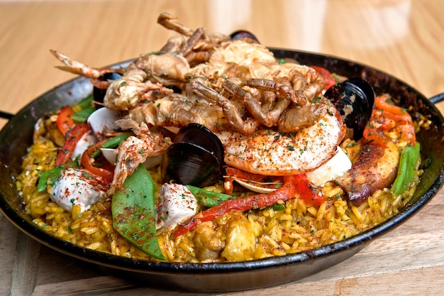 Paella con langostinos mejillones pescado y pulpo servido en una sartén sobre una mesa de madera comida gastronomía