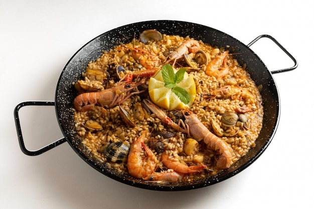 Paella de marisco español sobre fondo blanco.