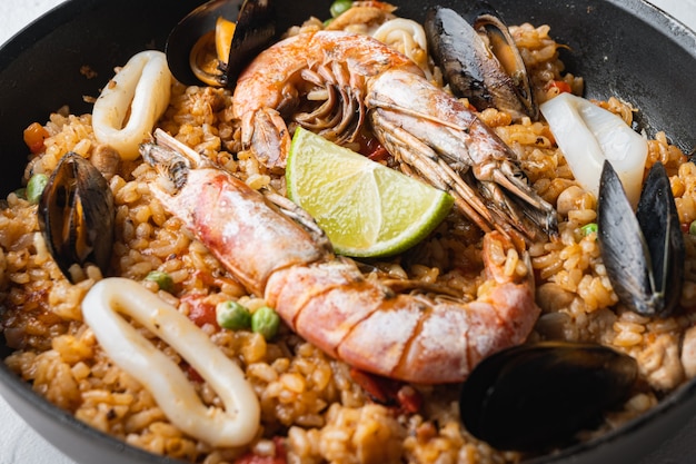 Paella de pollo y mariscos con arroz en sartén