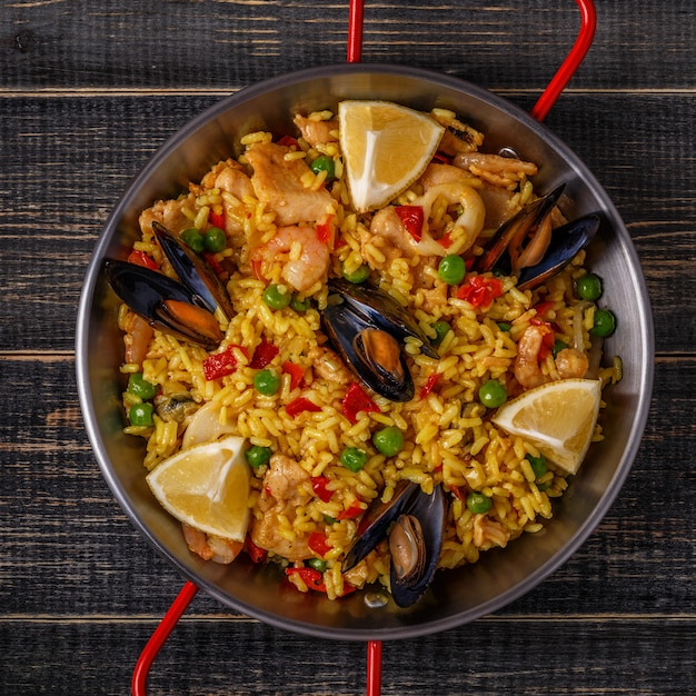 Paella con pollo, mariscos, verduras y azafrán servido en la sartén tradicional.