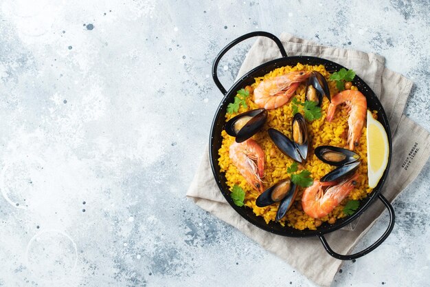 Foto paella tradicional española de mariscos en sartén con garbanzos, camarones, mejillones y calamares