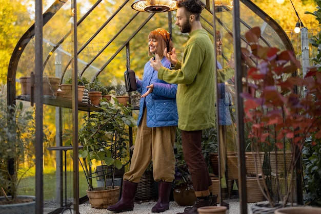 Pärchen kümmert sich um Pflanzen in kleiner Orangerie