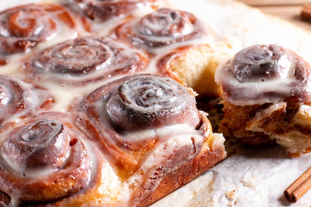 Pães de cinnabon recém-assados com molho de creme em cinnabons de papel manteiga no café da manhã