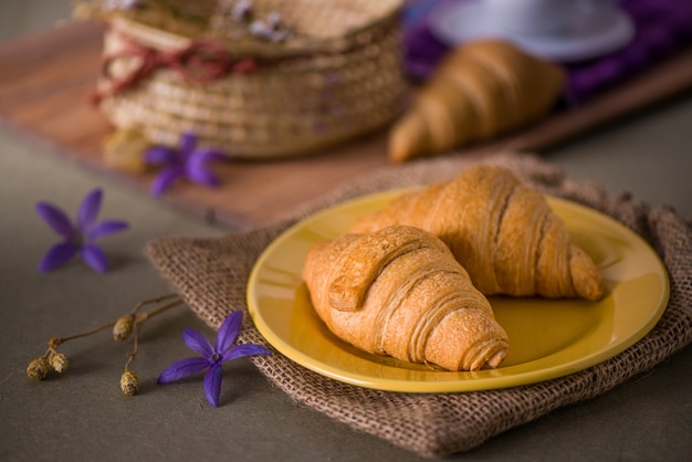 Pães de croissant em um prato amarelo na mesa do café