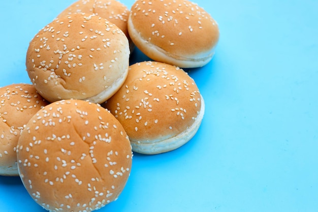 Pães de hambúrguer com gergelim sobre fundo azul.