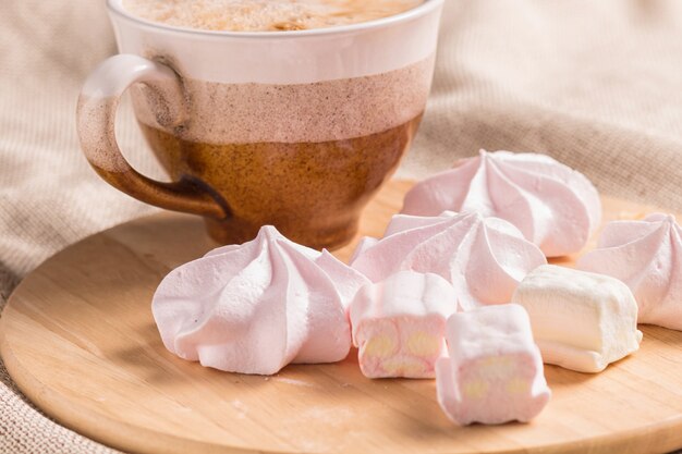 Pães doces, merengues e xícara de café em uma placa de madeira