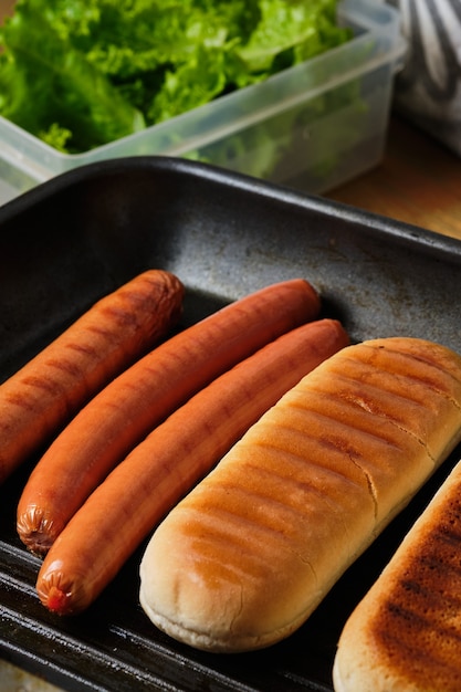 Pães e enchidos grelhados. Ingredientes de cachorro-quente. Processo de cozimento de cachorro-quente. Comida rápida.