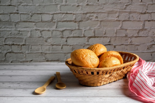 pães em uma cesta de vime em um fundo branco de madeira, com espaço de cópia, deliciosos pães caseiros