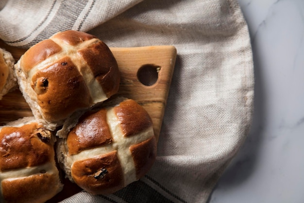 Pães transversais quentes tradicionais com passas em uma placa de madeira