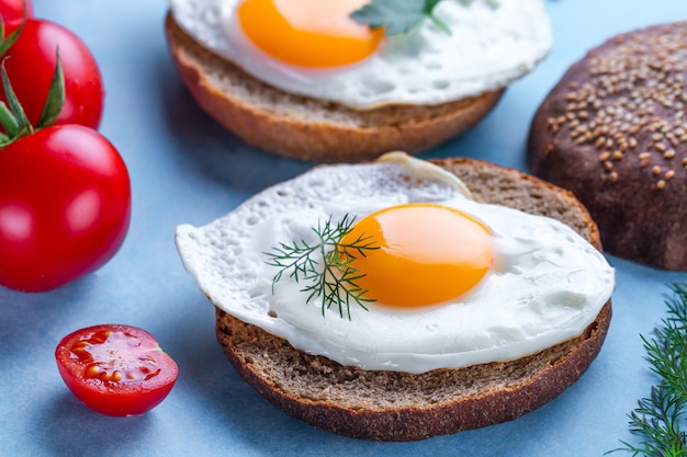 Pãezinhos com ovos de frango frito caseiros, para um café da manhã saudável em um surfce azul. Alimentos protéicos. Sanduíches de ovos