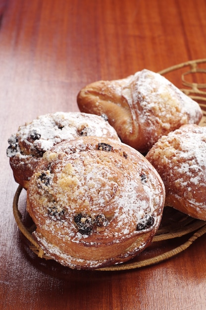 Pãezinhos com passas e maçãs na mesa de madeira