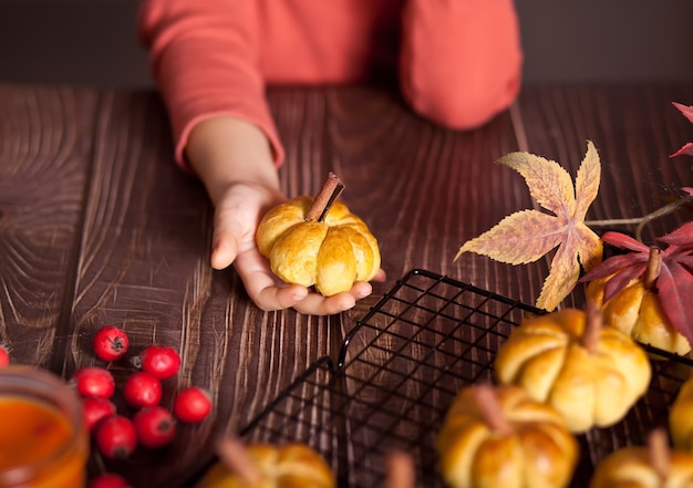 Foto pãezinhos de abóbora na assadeira. conceito de outono. menina, pegue um pão.