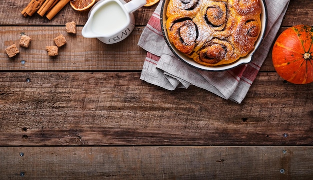 Pãezinhos de canela de canela com caramelo de abóbora e creme de açúcar gelado na mesa de fundo de madeira rústica Vista superior Doce pastelaria caseira cozimento de natal sobremesa sueca Kanelbule