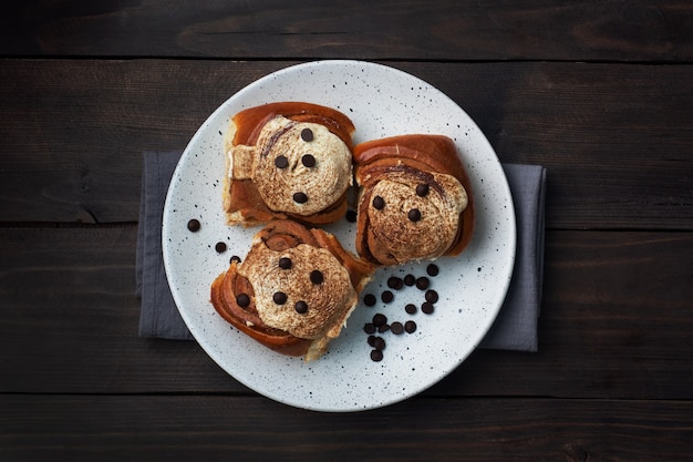 Pãezinhos de canela Kanelbulle com creme de manteiga em uma mesa de madeira rústica. Pastelaria fresca caseira.