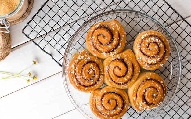 Pãezinhos de canela recém-assados com especiarias em um fundo de madeira. Kanelbule - sobremesa sueca. Conceito de comida. Vista superior, configuração plana