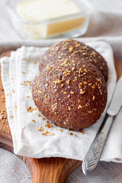 Pãezinhos de centeio caseiros com linhaça, sementes de gergelim e papoula branca na placa de madeira