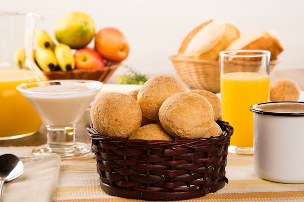 Foto pãezinhos de queijo brasileiro. mesa café da manhã com frutas e pão de queijo.